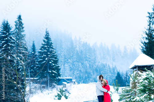 guy and girl in warm clothes with hoods on their heads hugging a