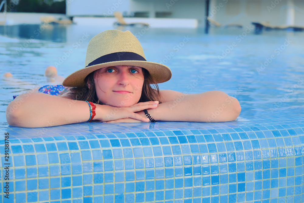 A woman in a straw hat lying in a pool of blue water