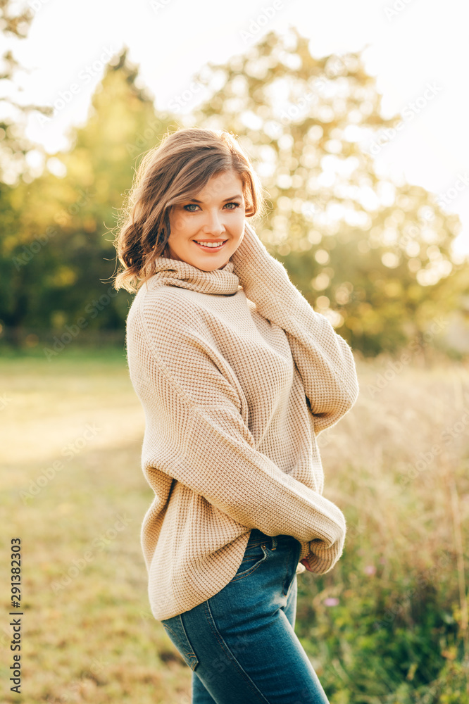 Outdoor portrait of beautiful young woman in the park, wearing warm knitted pullover Outdoor portrait of beautiful young woman in the park, wearing warm knitted pullover