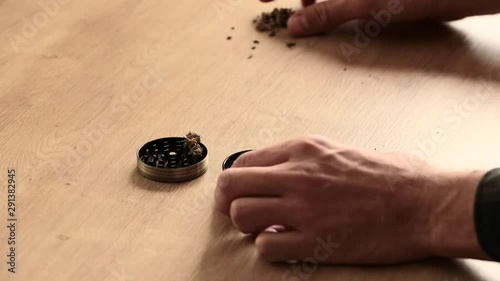 White male hands opening a grinder full of weed with paraphernalia on kitchen top down. Grinder full of legal medicinal marijuana for anxiety and medical use.