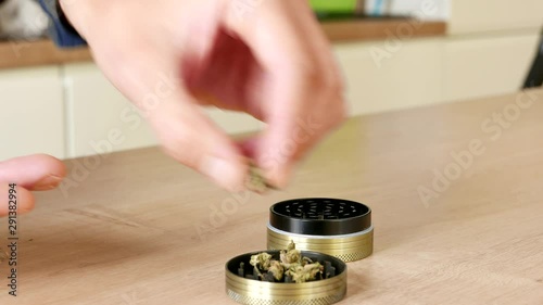 White male hands opening a grinder full of weed with paraphernalia on kitchen top down 4k. Grinder full of legal medicinal marijuana for anxiety and medical use.