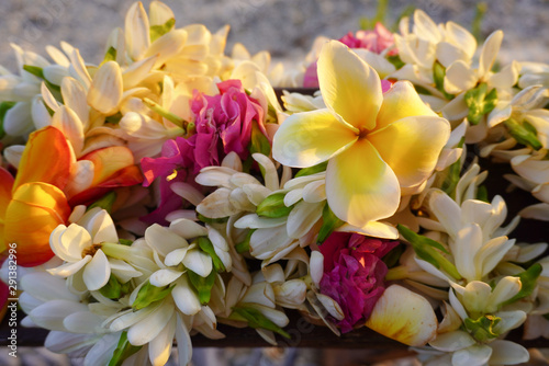 A bouquet of tropical flowers rests above a sandy beach in French Polynesia in the South Pacific