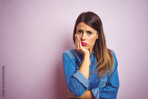 Young beautiful woman standing over pink isolated background thinking looking tired and bored with depression problems with crossed arms.