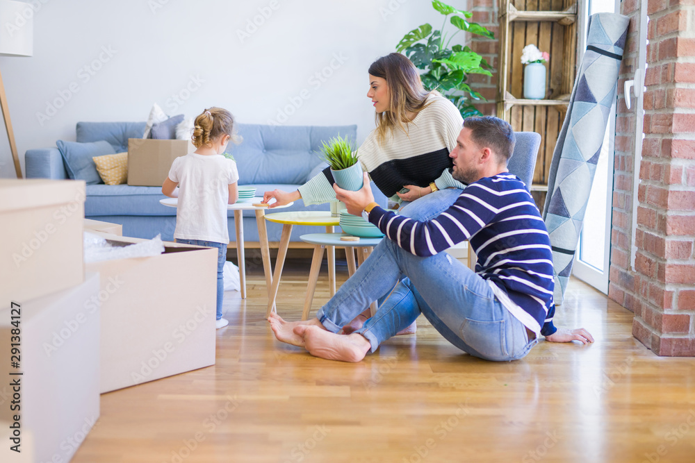 Beautiful family sitting on the floor playing with his kid at new home around cardboard boxes Beautiful family sitting on the floor playing with his kid at new home around cardboard boxes