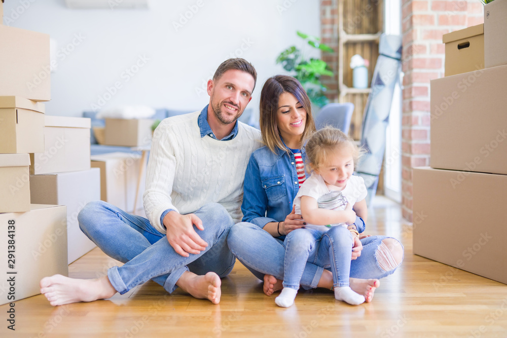 Beautiful family sitting on the floor playing with his kid at new home around cardboard boxes Beautiful family sitting on the floor playing with his kid at new home around cardboard boxes