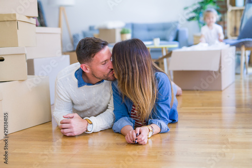 Beautiful famiily with kid lying down at new home around cardboard boxes