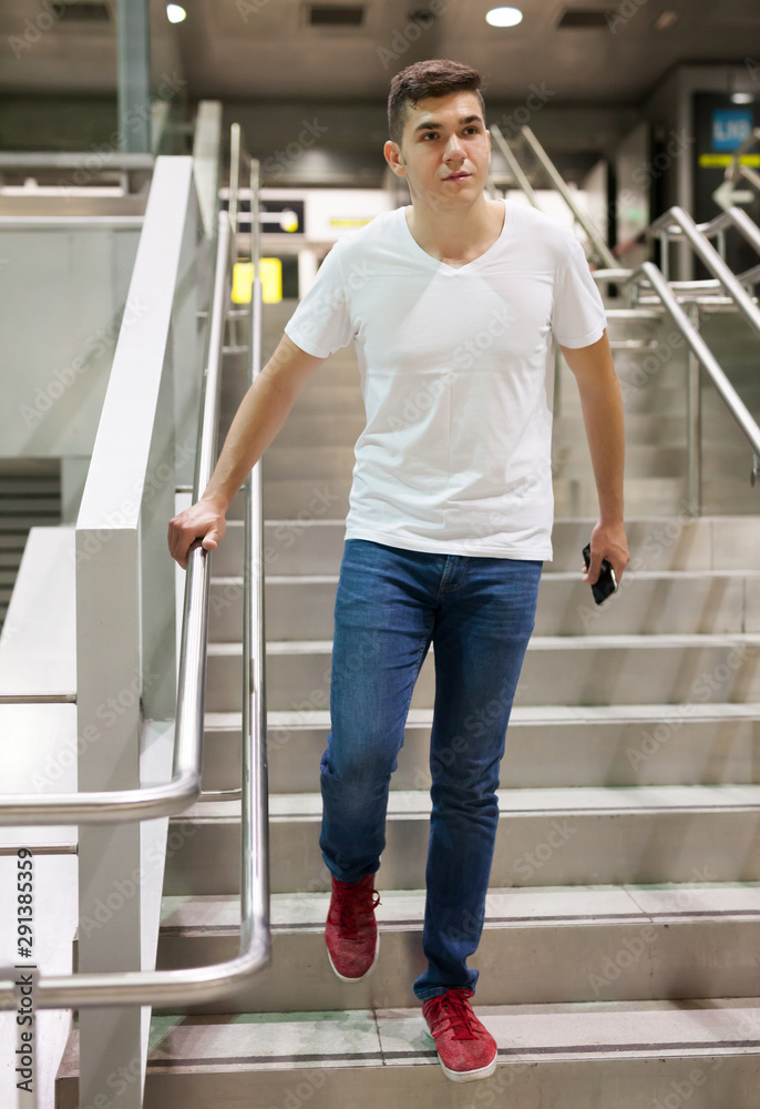 Man with phone on stairs of subway