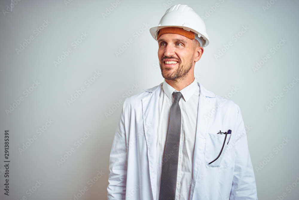 Young handsome engineer man wearing safety helmet over isolated background looking away to side with smile on face, natural expression. Laughing confident. Young handsome engineer man wearing safety helmet over isolated background looking away to side with smile on face, natural expression. Laughing confident.