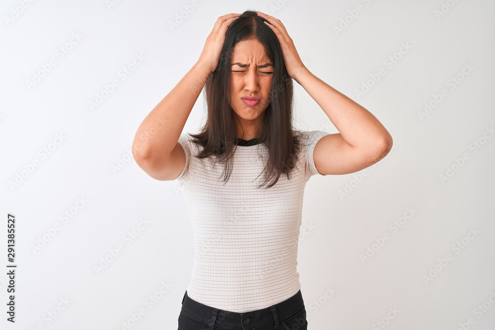 Young beautiful chinese woman wearing casual t-shirt standing over isolated white background suffering from headache desperate and stressed because pain and migraine. Hands on head.