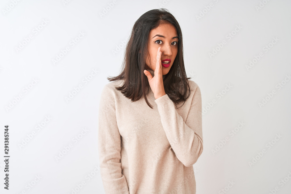 Beautiful chinese woman wearing turtleneck sweater standing over isolated white background hand on mouth telling secret rumor, whispering malicious talk conversation