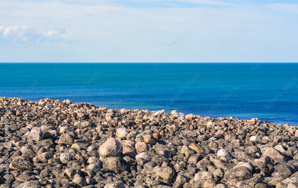 Just rocks and a calm sea. Round stones washed by the waters of the Arctic ocean. The deep blue color of the sea inspires, sets up a romantic mood. Barents sea, near Teriberka, Murmansk oblast Just rocks and a calm sea. Round stones washed by the waters of the Arctic ocean. The deep blue color of the sea inspires, sets up a romantic mood. Barents sea, near Teriberka, Murmansk oblast
