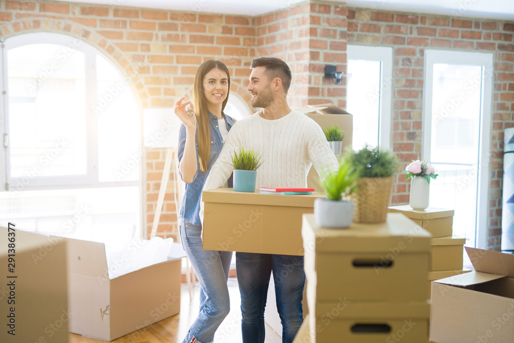 Young couple moving to a new home, hugging in love showing keys of new apartment smiling very happy Young couple moving to a new home, hugging in love showing keys of new apartment smiling very happy