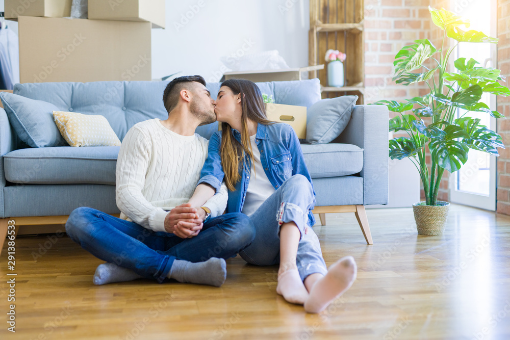 Young beautiful couple sitting on the floor of new apartment, smiling in love happy for moving to a new home Young beautiful couple sitting on the floor of new apartment, smiling in love happy for moving to a new home