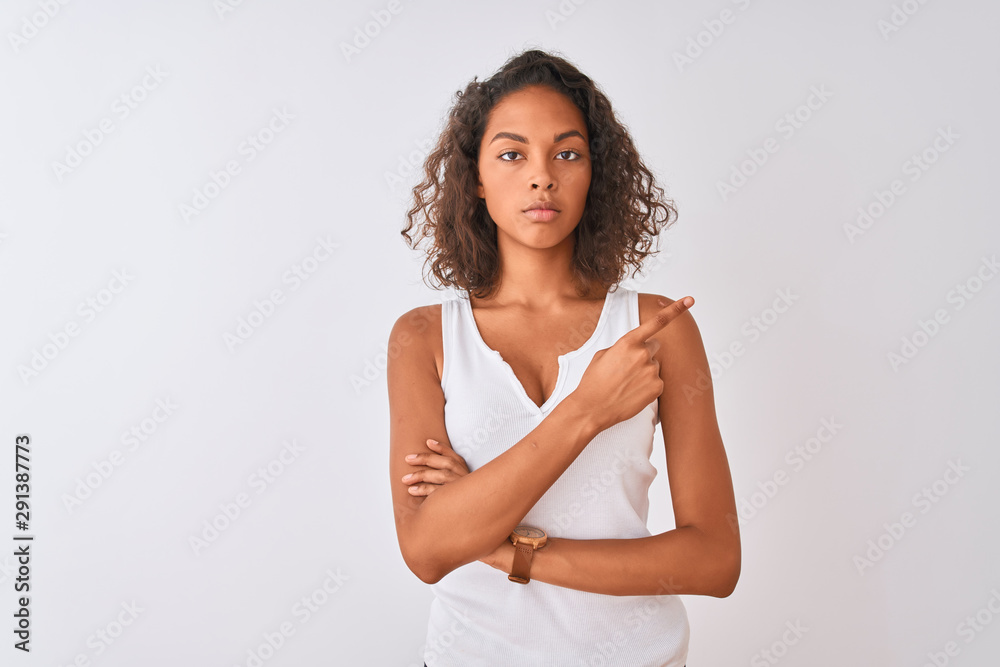 Young brazilian woman wearing casual t-shirt standing over isolated white background Pointing with hand finger to the side showing advertisement, serious and calm face Young brazilian woman wearing casual t-shirt standing over isolated white background Pointing with hand finger to the side showing advertisement, serious and calm face