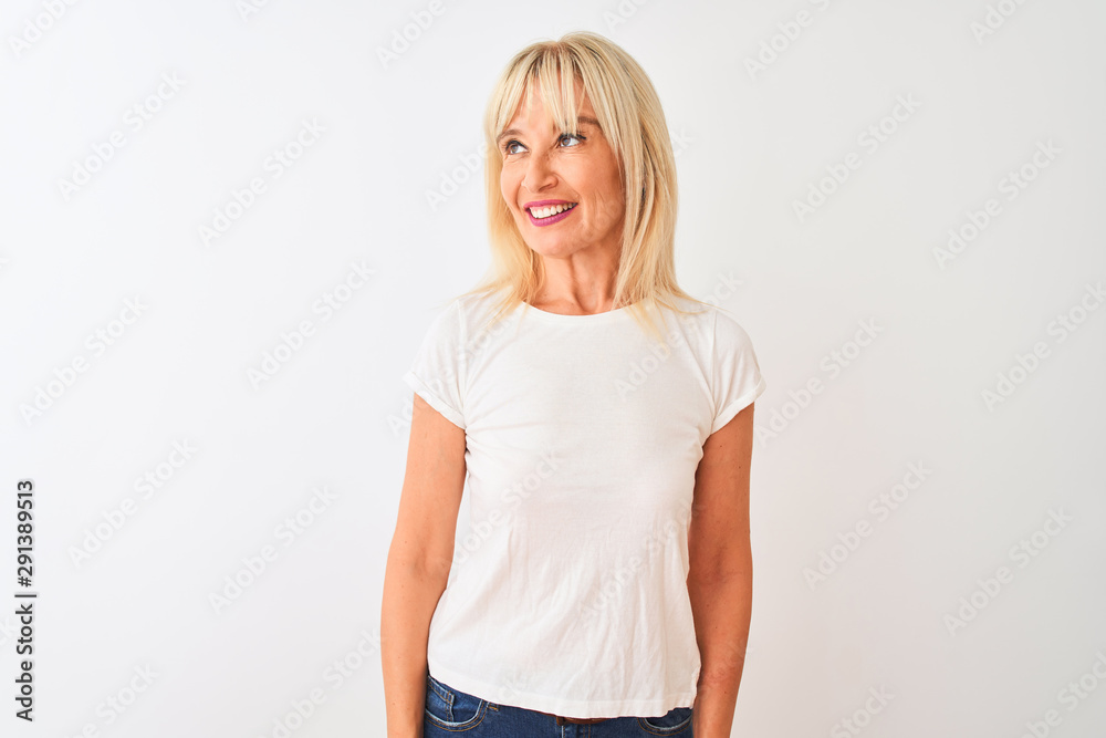 Middle age woman wearing casual t-shirt standing over isolated white background smiling looking to the side and staring away thinking.