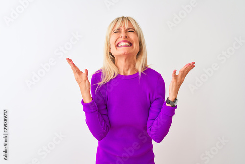 Middle age woman wearing purple t-shirt standing over isolated white background celebrating mad and crazy for success with arms raised and closed eyes screaming excited. Winner concept © Krakenimages.com