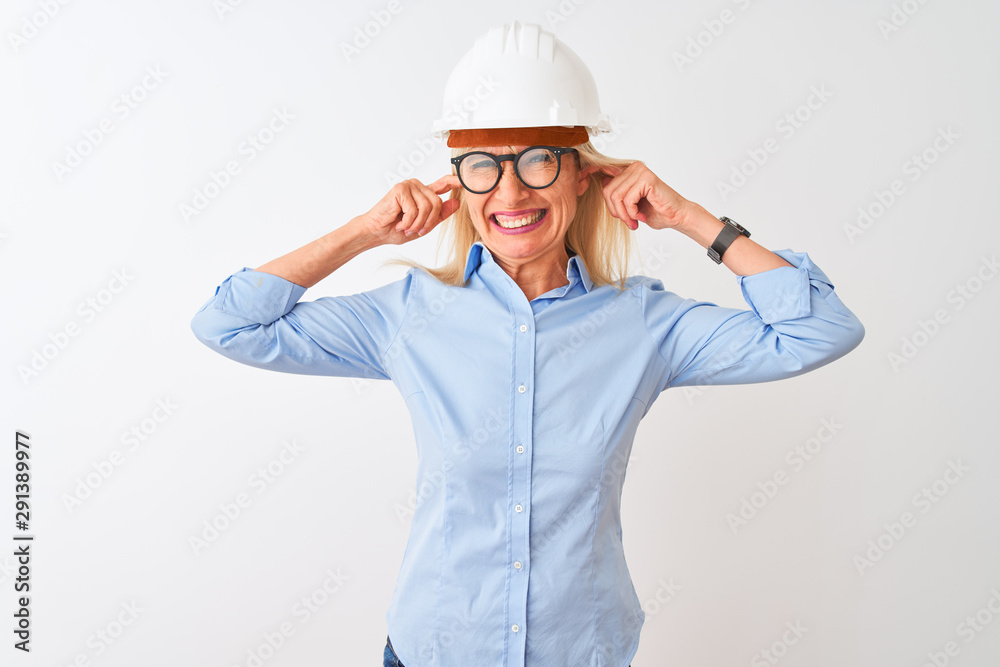 Middle age architect woman wearing glasses and helmet over isolated white background covering ears with fingers with annoyed expression for the noise of loud music. Deaf concept.