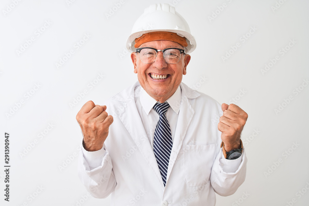 Senior grey-haired engineer man wearing coat and helmet over isolated white background celebrating surprised and amazed for success with arms raised and open eyes. Winner concept.