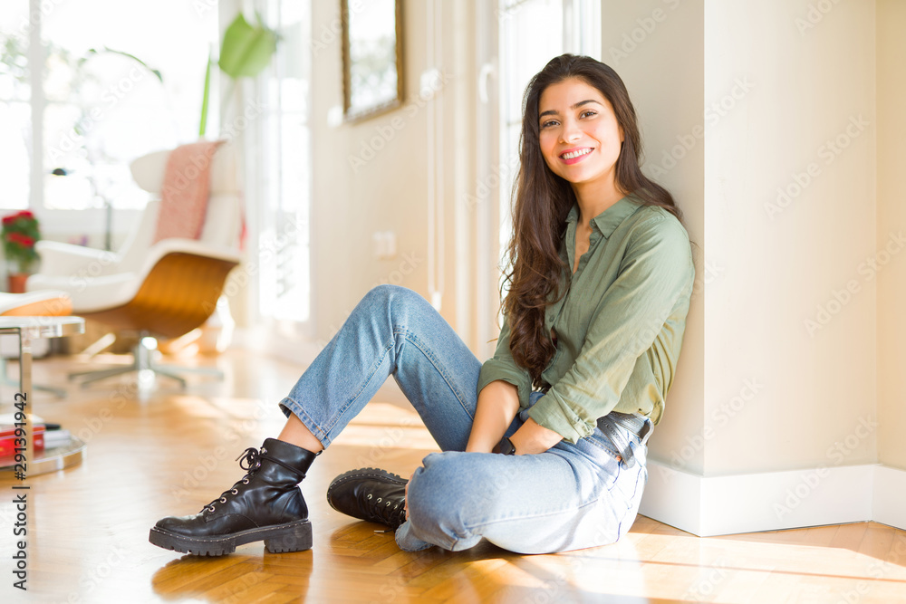 Young beautiful woman sitting on the floor at home with a happy and cool smile on face. Lucky person.