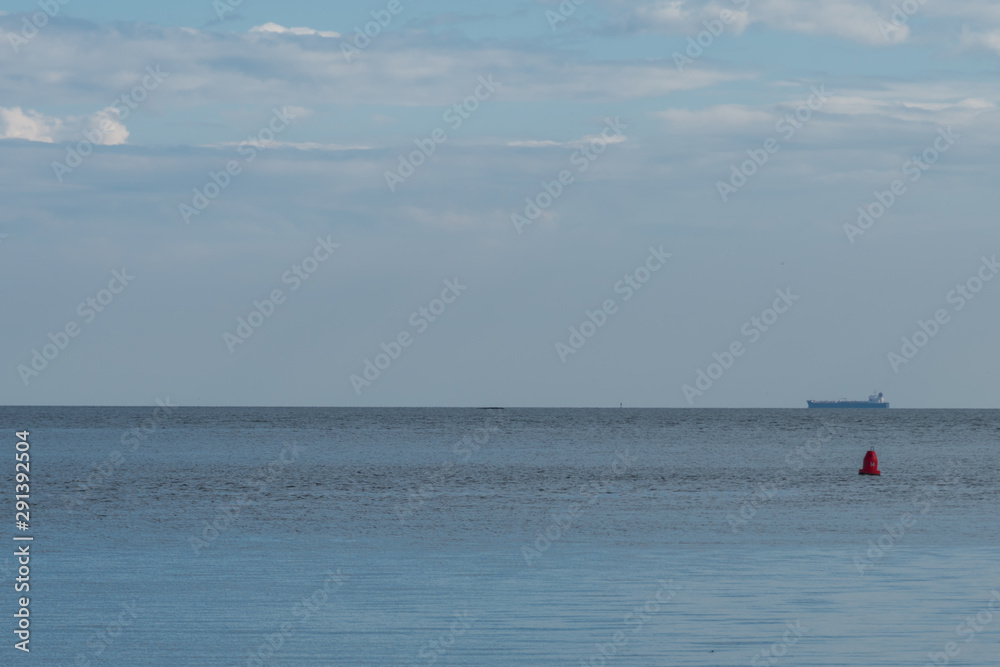 Distant ship on horizon of Long Island Sound with red buoy in mid ground on summer afternoon