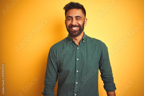 Young indian businessman wearing elegant shirt standing over isolated white background winking looking at the camera with sexy expression, cheerful and happy face.