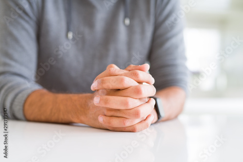 Close up of man with crossed hands over white table