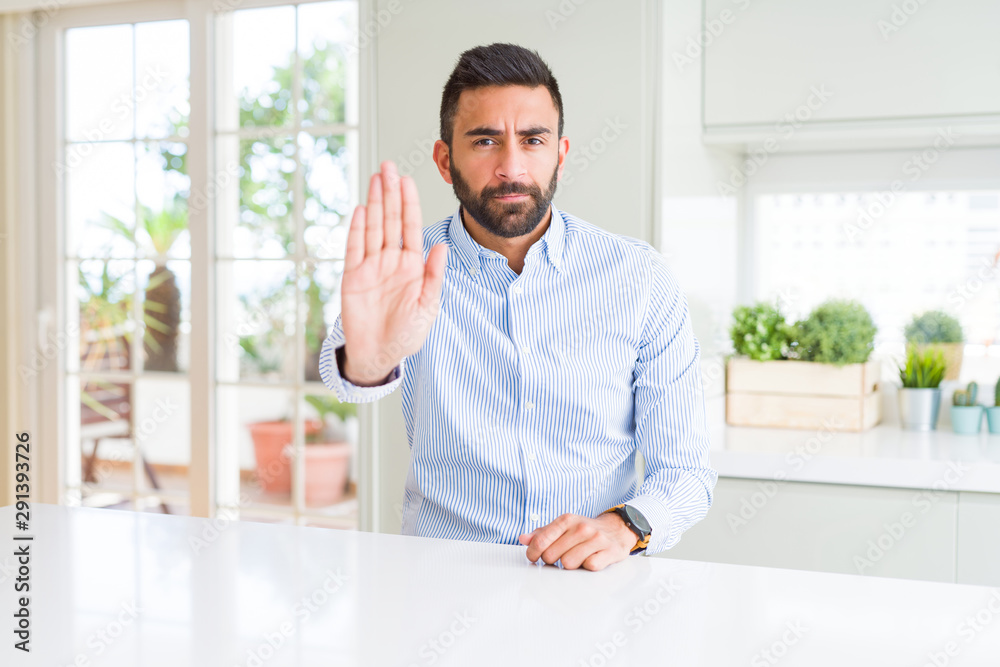 Handsome hispanic business man doing stop sing with palm of the hand. Warning expression with negative and serious gesture on the face.