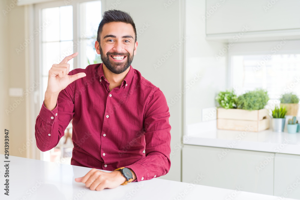 Handsome hispanic business man smiling and confident gesturing with hand doing size sign with fingers while looking and the camera. Measure concept.