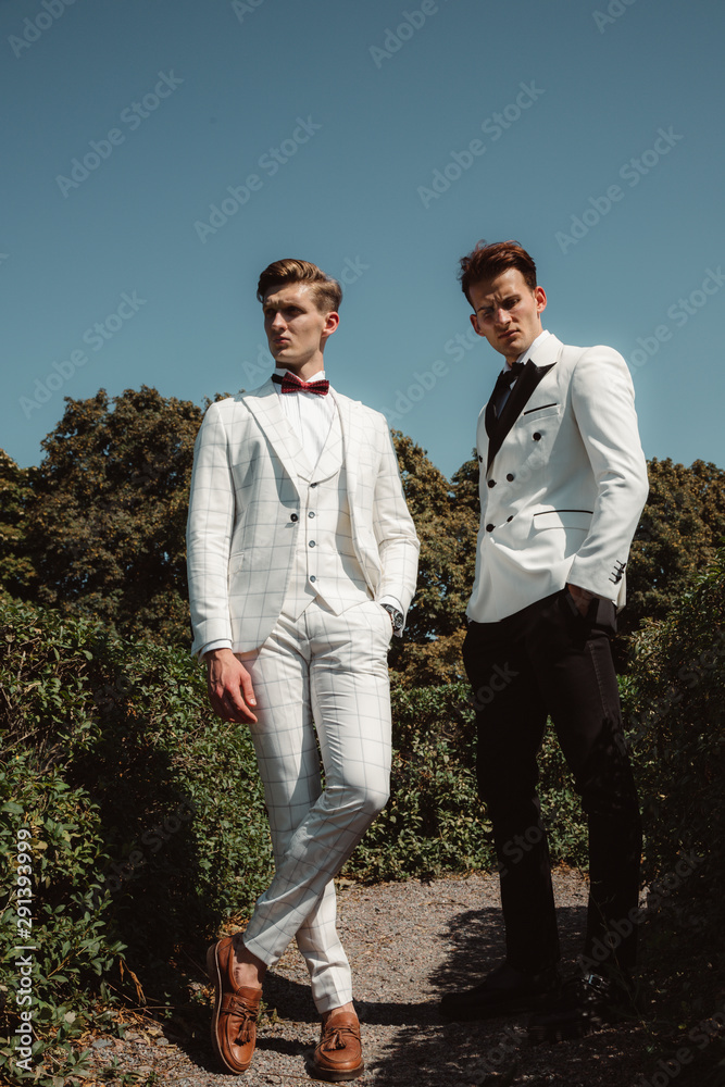 Young and handsome guys in classic suits posing in the park. Outdoor shot. Young and handsome guys in classic suits posing in the park. Outdoor shot.