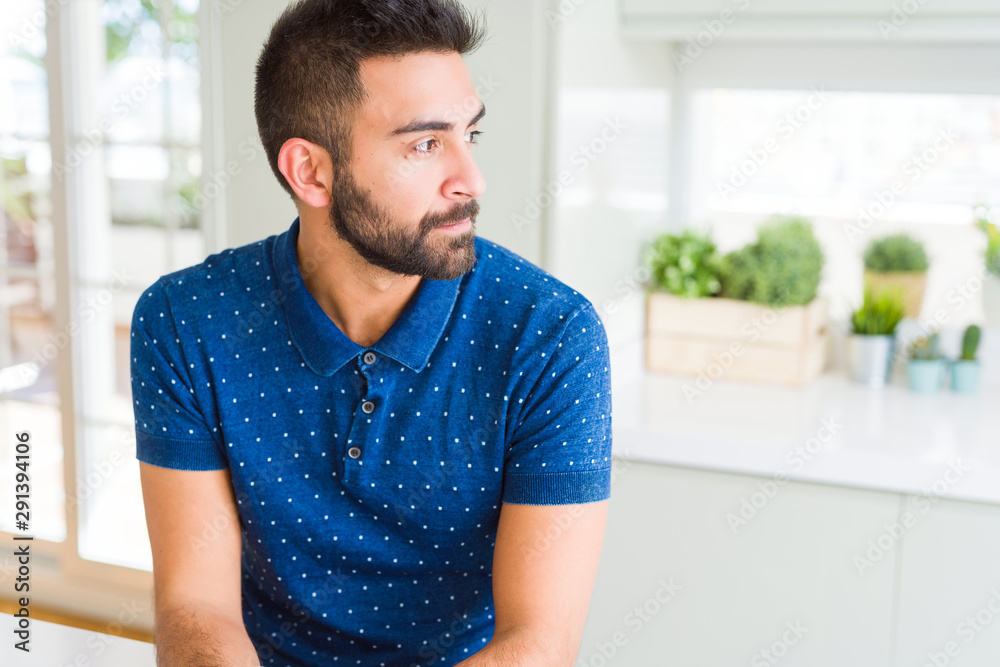 Fototapeta premium Handsome hispanic man at home looking to side, relax profile pose with natural face with confident smile.