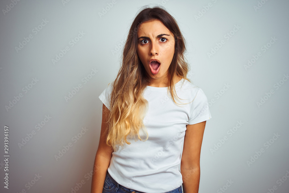 Young beautiful woman wearing casual white t-shirt over isolated background In shock face, looking skeptical and sarcastic, surprised with open mouth Young beautiful woman wearing casual white t-shirt over isolated background In shock face, looking skeptical and sarcastic, surprised with open mouth