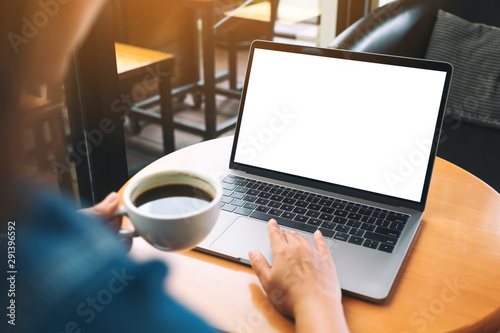 Mockup image of a hand using and touching on laptop touchpad with blank white desktop screen while drinking coffee