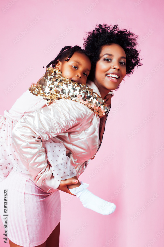 young pretty african-american mother with little cute daughter hugging, happy smiling on pink background, lifestyle modern people concept young pretty african-american mother with little cute daughter hugging, happy smiling on pink background, lifestyle modern people concept