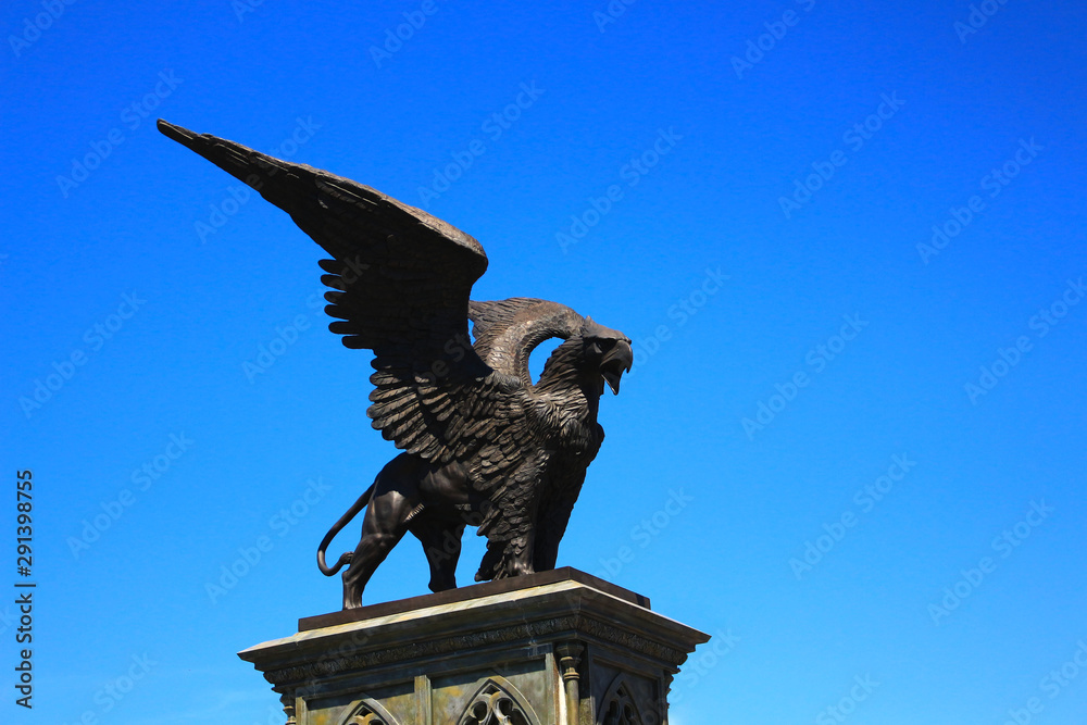 Statue of Griffin or Griffon against the sky. A legendary creature with the body of a lion, the head and wings of an eagle. Ancient mythology fantasy