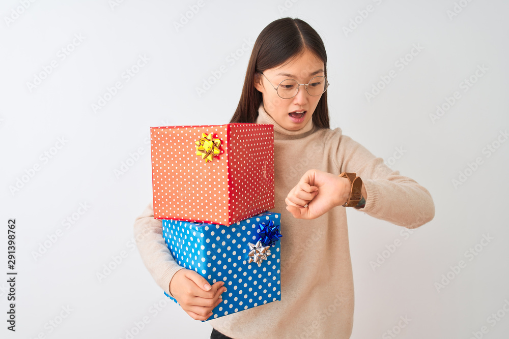 Young chinese woman holding birthday gifts over isolated white background Looking at the watch time worried, afraid of getting late Young chinese woman holding birthday gifts over isolated white background Looking at the watch time worried, afraid of getting late