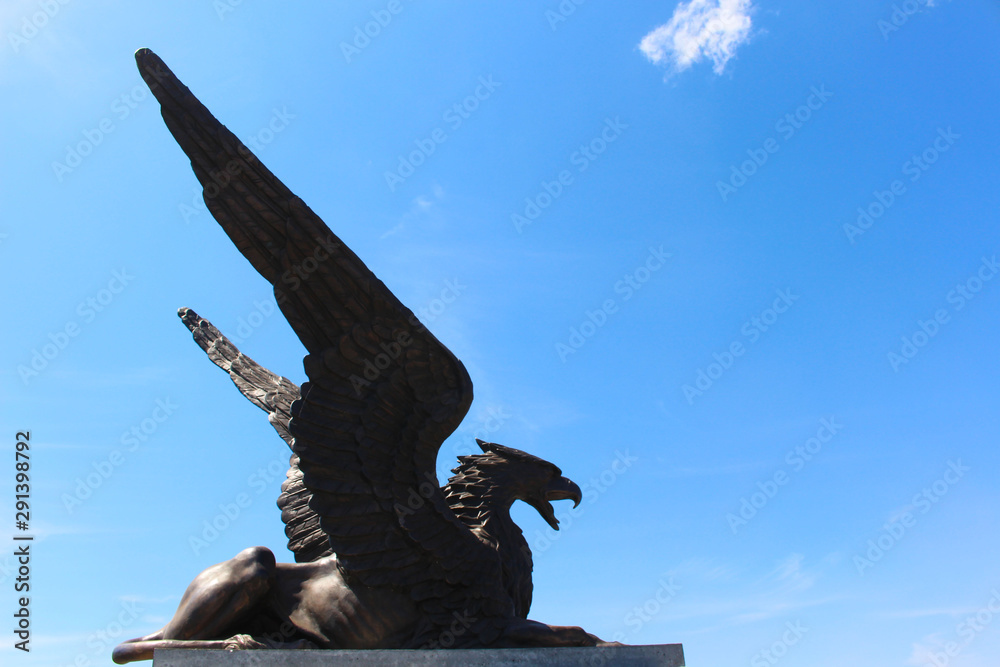 Fototapeta premium Statue of Griffin or Griffon against the sky. A legendary creature with the body of a lion, the head and wings of an eagle. Ancient mythology fantasy