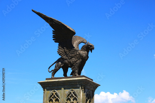 Statue of Griffin or Griffon against the sky. A legendary creature with the body of a lion, the head and wings of an eagle. Ancient mythology fantasy