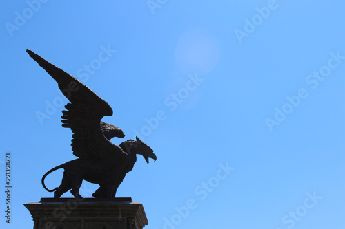 Statue of Griffin or Griffon against the sky. A legendary creature with the body of a lion, the head and wings of an eagle. Ancient mythology fantasy photo