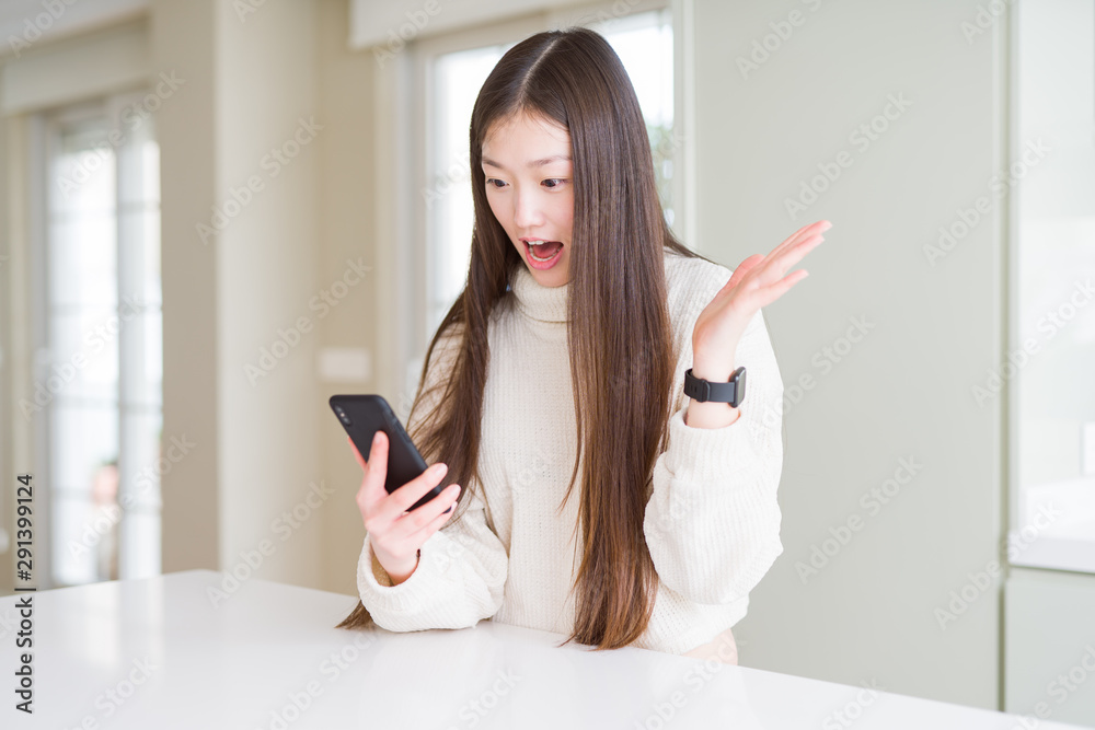 Beautiful Asian woman using smartphone very happy and excited, winner expression celebrating victory screaming with big smile and raised hands Beautiful Asian woman using smartphone very happy and excited, winner expression celebrating victory screaming with big smile and raised hands