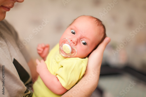 Portrait of happy young caucasian father holding his newborn baby indoor in selective focus.