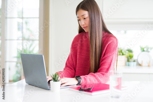 Beautiful Asian woman working using computer laptop with a confident expression on smart face thinking serious