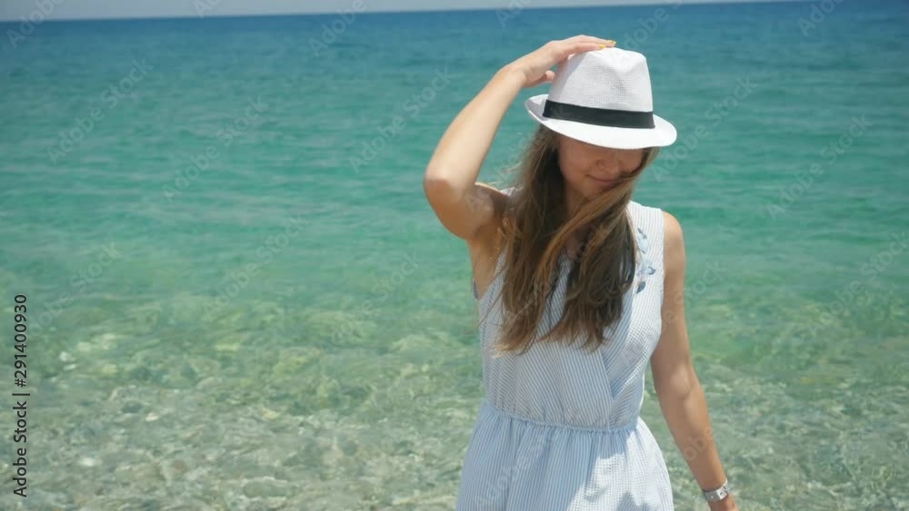 Young beautiful caucasian girl with white hat walks along the beach coastal view Young beautiful caucasian girl with white hat walks along the beach coastal view