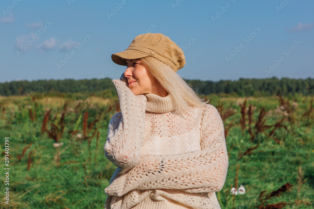 Obraz premium Happy beautiful blond woman walking in a green field