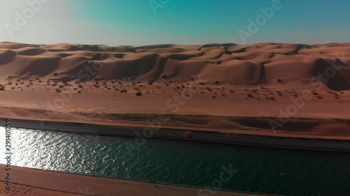 Smooth sideways pan of Waterway in front of vast Arizona desert Sand dunes
