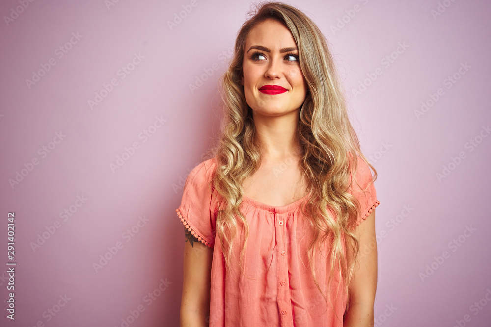 Young beautiful woman wearing t-shirt standing over pink isolated background smiling looking to the side and staring away thinking. Young beautiful woman wearing t-shirt standing over pink isolated background smiling looking to the side and staring away thinking.