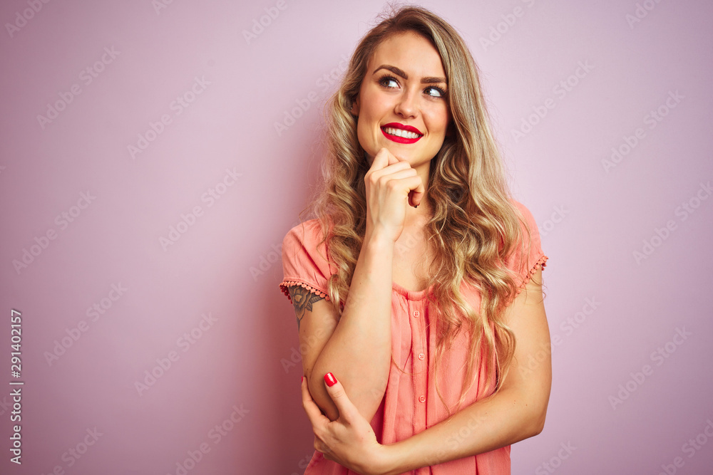 Young beautiful woman wearing t-shirt standing over pink isolated background with hand on chin thinking about question, pensive expression. Smiling and thoughtful face. Doubt concept. Young beautiful woman wearing t-shirt standing over pink isolated background with hand on chin thinking about question, pensive expression. Smiling and thoughtful face. Doubt concept.