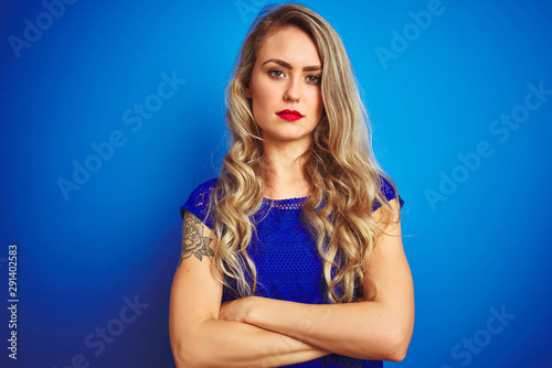 Young beautiful woman standing over blue isolated background skeptic and nervous, disapproving expression on face with crossed arms. Negative person.