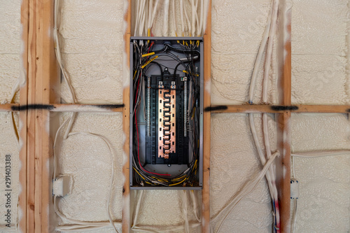 Electrical Circuit Breaker panel in new home construction, with spray foam insulation and negative space photo