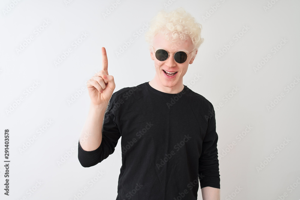 Naklejka premium Young albino man wearing black t-shirt and sunglasess standing over isolated white background pointing finger up with successful idea. Exited and happy. Number one.