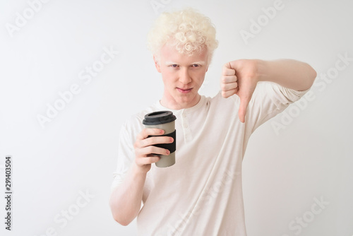 Young albino blond man drinking coffee standing over isolated white background with angry face, negative sign showing dislike with thumbs down, rejection concept